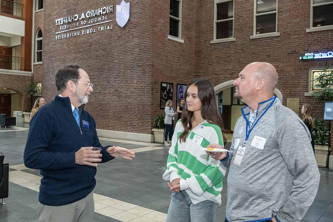 The dean of the Chaifetz School of Business talks to guests at an open house.